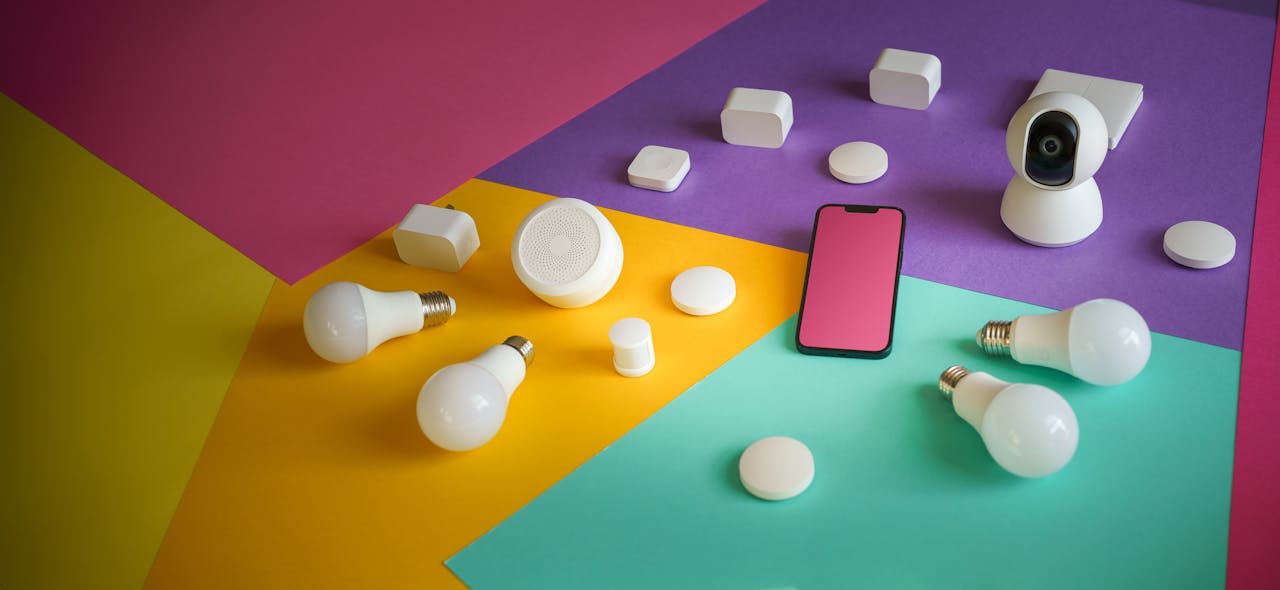 Services A vibrant display of smart home devices including bulbs, sensors, and a smartphone on a colorful background.